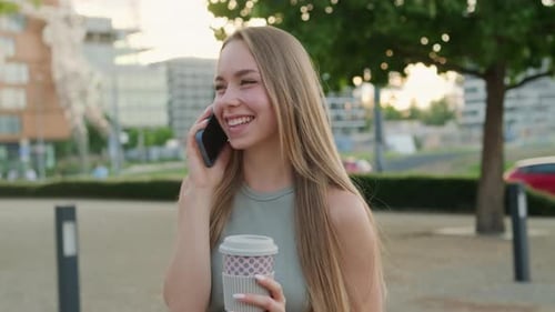 Woman Talking on Mobile Phone Holding Coffee
