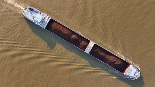 Large cargo vessel, tarpaulin covered goods, murky river waters, aerial