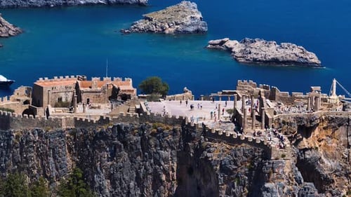Drone filmé par téléobjectif en orbite autour de l'Acropole de Lindos, sous le soleil de Rhodes, en Grèce