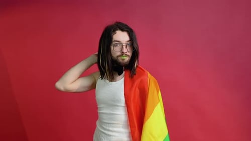 Person with Pride Flag Posing Against Red Backdrop