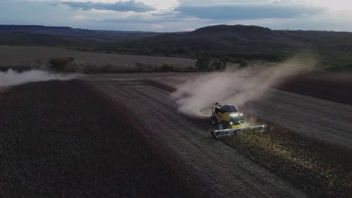 Combine Harvesters Working in Field at Night Aerial View
