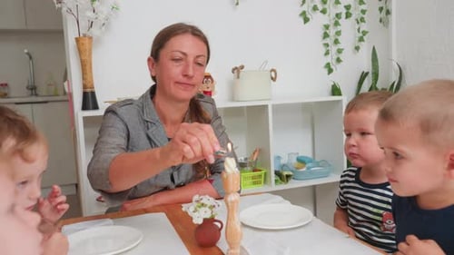 Woman Lits Candle with Children at Table
