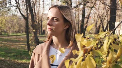Portrait of Young Attractive Blonde Woman Walking in the Autumn Park on Sunset