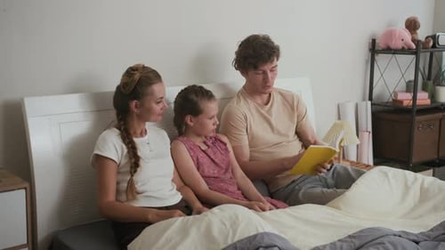 Family Enjoying Story Time on Bed at Home