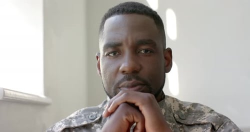 Un soldat afro-américain en uniforme militaire semble contemplatif chez lui