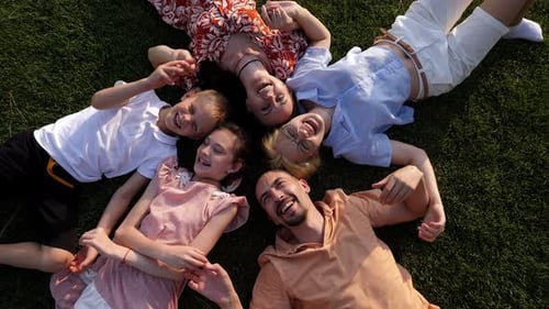 Closeup of a Cheerful Big Family Lying Down Together on the Grass in a Circle