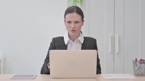 Businesswoman Massaging Stiff Neck at Desk