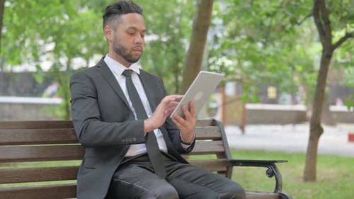 Mixed Race Businessman Using Digital Tablet while Sitting Outdoor