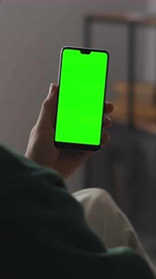 Person Holding Modern Smartphone with Vivid Green Chroma Key Screen Indoors Showcasing Blank Display