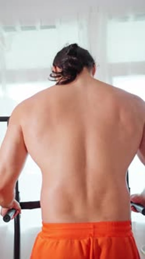 Man Stretches Workout Prep Man with Ponytail Stretches Muscles Before Workout Session in Home Gym