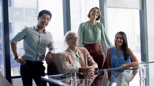 Smiling business team posing together around conference table in modern office