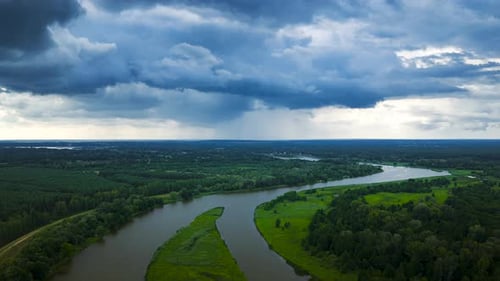Time lapse drone shot of clouds at sky over green nature with river and cars on road. Aerial wide sh