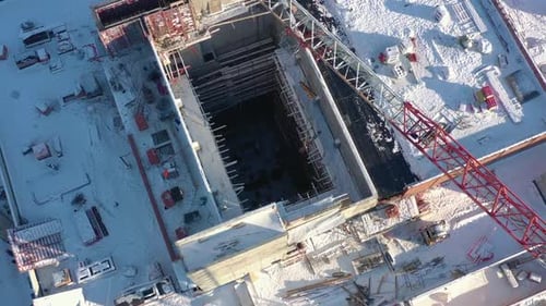 Una grúa transporta carga sobre un edificio industrial sin terminar