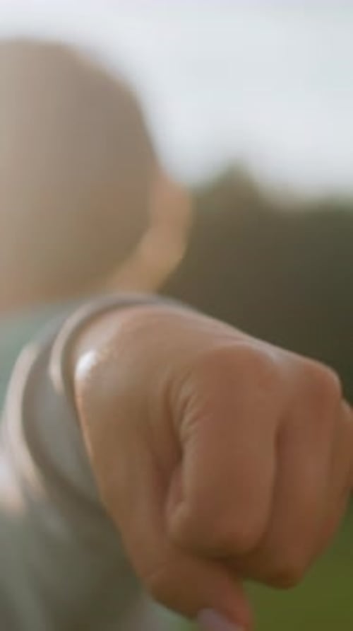 Woman Extends Fist in Nature Setting, Close Up