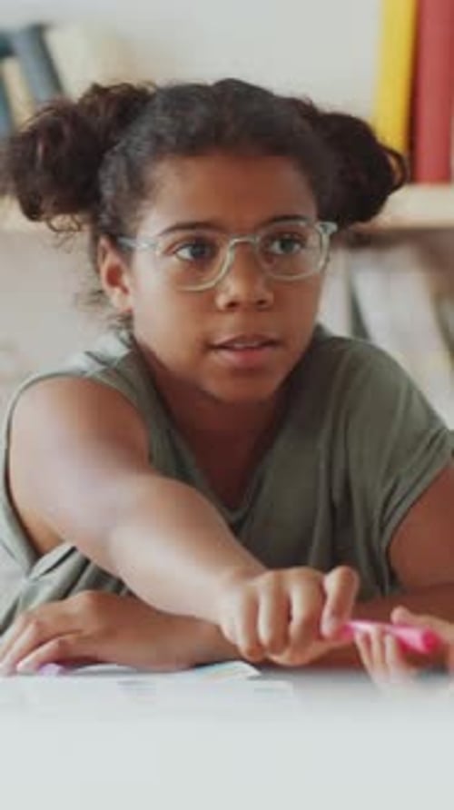 African American Girl Sharing Pencils with Classmate During Lesson in school