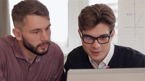 Young Adults Collaborating on Laptop in Workplace