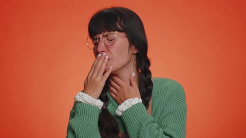 Woman Coughing and Touching Throat on Orange Background