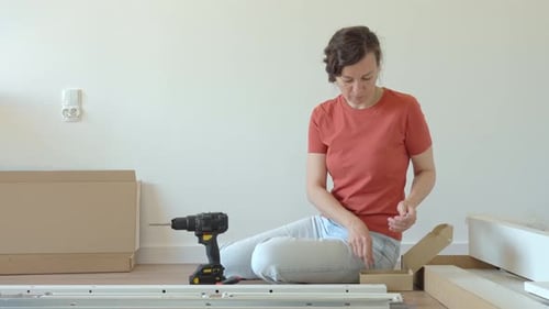Woman assembling furniture on floor at home