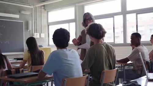 Teacher Handing Papers to Students in a Classroom Setting