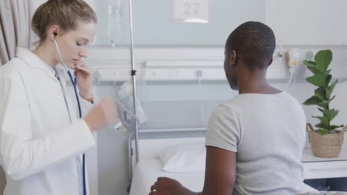 Diverse female patient and doctor, using stethoscope on her back in hospital, in slow motion