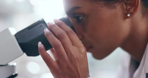 Woman Using Microscope in Brightly Lit Lab