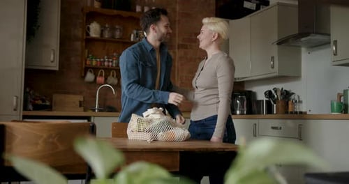 Couple Unpacking Groceries in Modern Kitchen Together