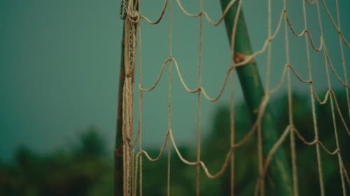 Football net in the rain on a soccer field with blurred background and green pole