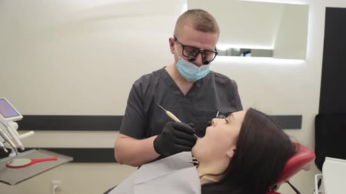 Dentist examining patient in chair at modern clinic