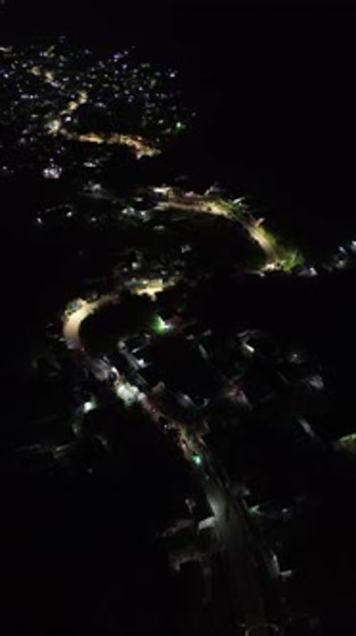 Vertical drone footage of the vehicles driving on illuminated highway roads in the city at night
