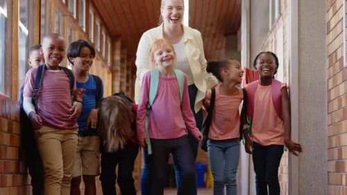 Group of school children walking in hallway with backpacks, smiling and talking