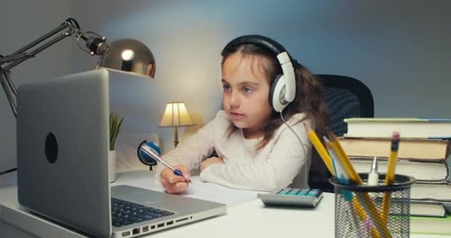 Young Girl Studying at Desk with Laptop and Headphones