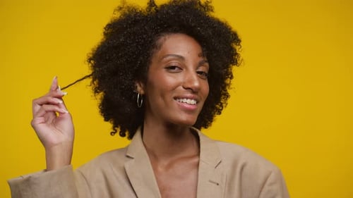 Beautiful Woman with Curly Hair Smiling on Yellow