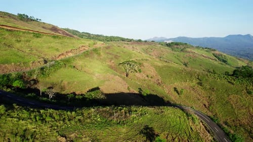 Aerial drone view of a winding road in a green mountain valley
