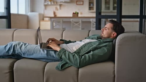 Man Relaxes with Laptop on Couch at Home