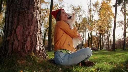 Woman Cuddling Dog in Sunny Autumn Park