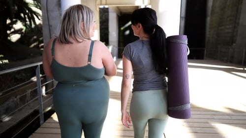 Two women in activewear walking together outdoors