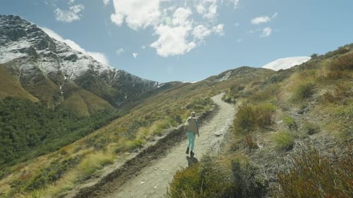 Woman Hikes Mountain Trail in Scenic Landscape
