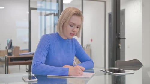 Young African Man Writing a Letter in Office