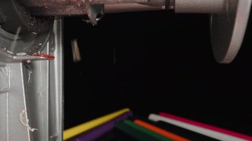 I sharpen a red pencil, shavings fly. Dolly slider extreme close-up.