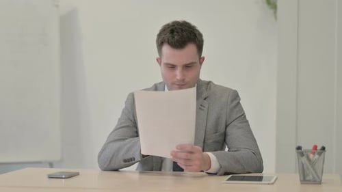 Enthusiastic Young Professional Reviews Documents at Office