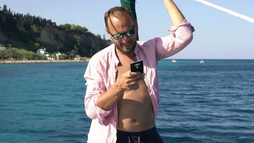 Young Man Texting on Smartphone While Sailing Boat on Sea Adult