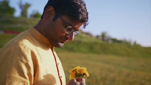 Indian Man Smelling a Dandelion Flower in a Field