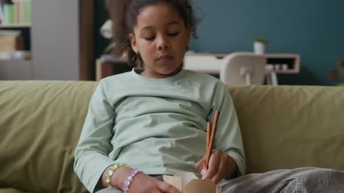 Girl Eating Noodles on Couch Inside Home