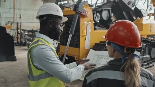 Multiethnic Coworkers Discussing Engineering Schemes at Tractor Plant
