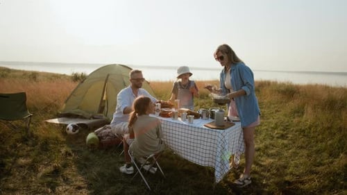Family Preparing Meal at Campsite by Lake on Summer Day