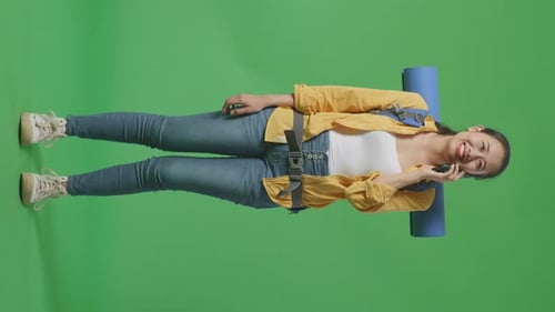 Full Body Of Asian Female Hiker Smiling And Talking On Smartphone While Standing On Green Screen