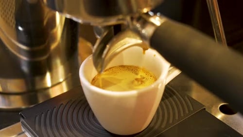 Rich Golden Crema Espresso Extraction into White Cup at Modern High-End Coffee