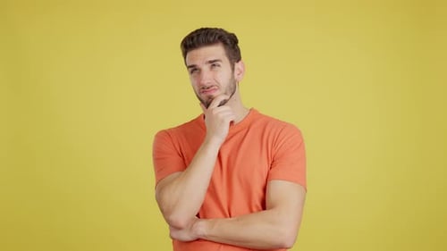 Pensive Young Man Thinking on Yellow Background