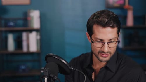Portrait of Young Man in Glasses Talks in Mic at Podcast in Audio Studio