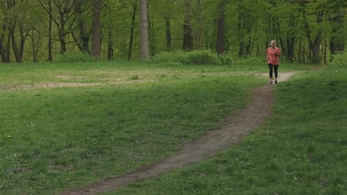 Senior Woman Running Jogging in Green Park Elderly Retired Female in Pink
